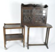 Three pieces of early 20th century furniture including an oak table, a dumb waiter, a wall cabinet,