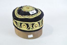 A Middle Eastern black velvet cap and a wooden hat block,