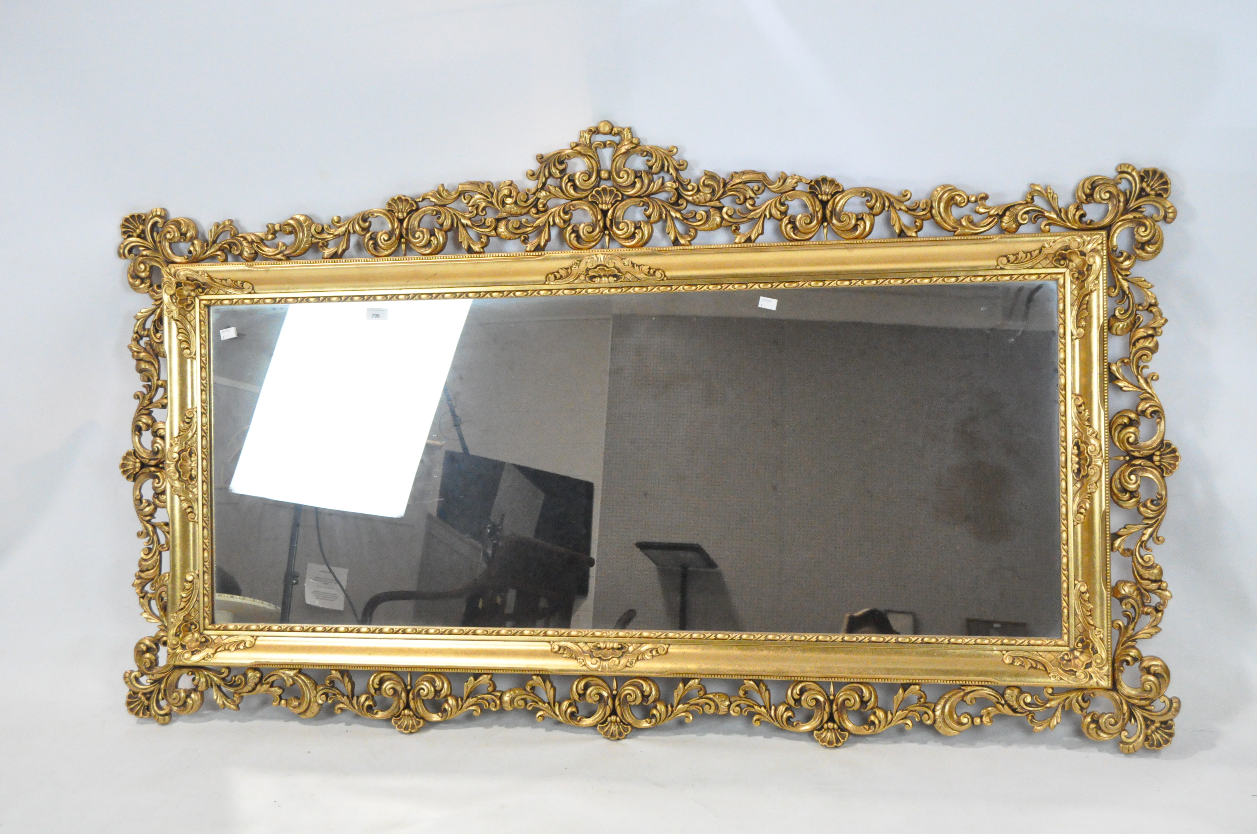A large contemporary gilt framed wall mirror, featuring an ornate pierced frame,