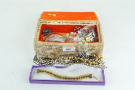 A collection of costume jewellery contained within a fabric mounted jewellery casket
