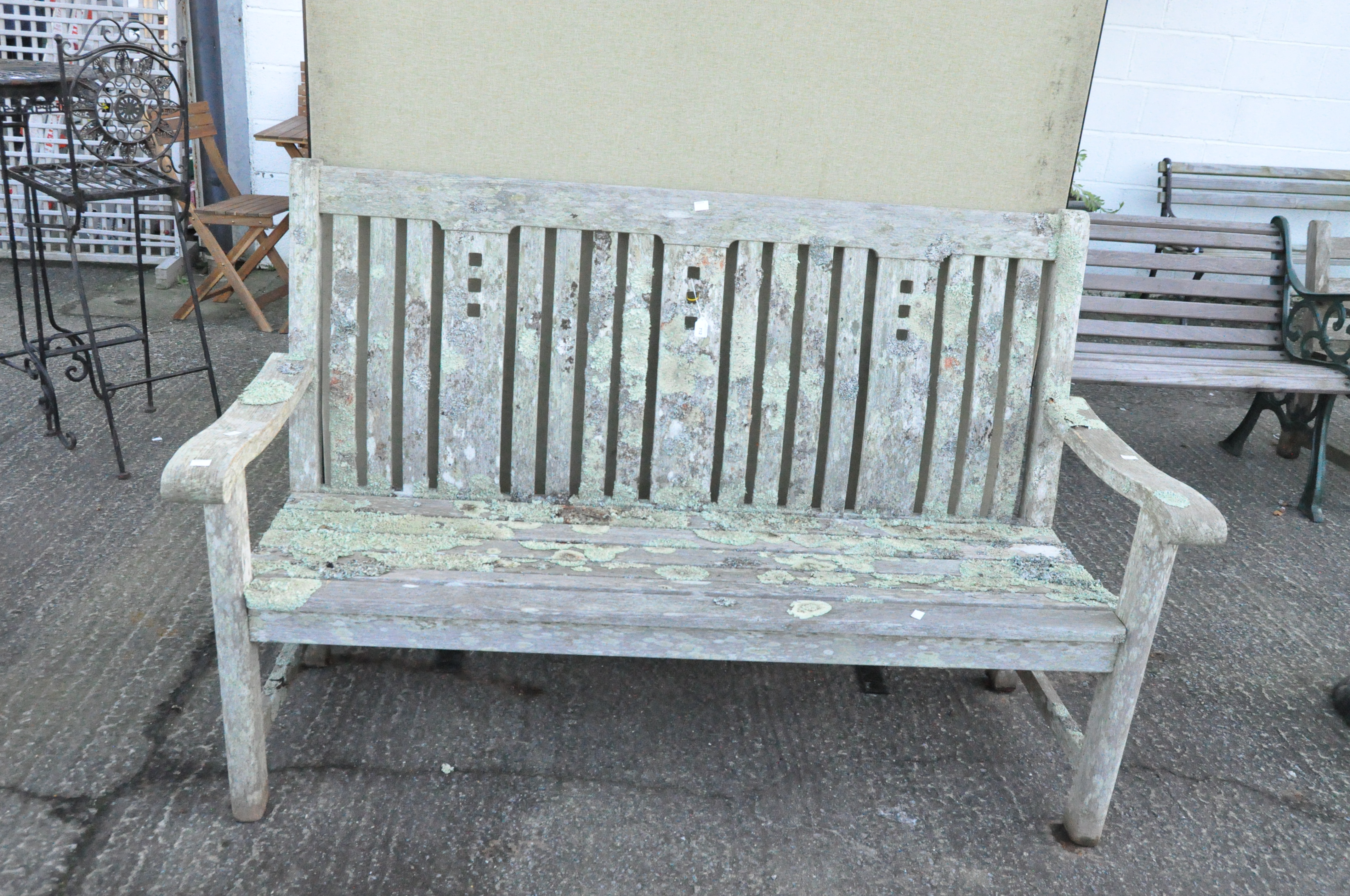A vintage slatted garden bench with pierced back splats,
