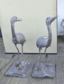 Two contemporary metal sculptures in the form of cranes standing on square stands,