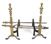 A pair of large brass fire dogs together with other fireside utensils.