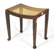 A vintage limed oak stool by the Bowman brothers, with attached label to base and caned seat,