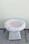 A 20th century heavy stone bird bath raised upon a trapezoidal prism base with large circular top,