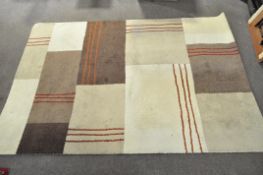 A contemporary ground rug, designed with a geometric pattern in cream and varied shades of brown,