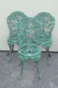 Three green ornate cast iron chairs with pierced grape and vine decoration,