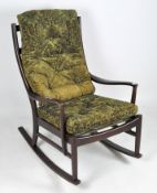 A Parker Knoll rocking chair, the wooden frame holding two green upholstered cushions,