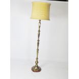 A 20th century standard lamp, the brass stand on a circular wooden base, with a yellow shade,