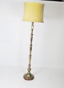 A 20th century standard lamp, the brass stand on a circular wooden base, with a yellow shade,