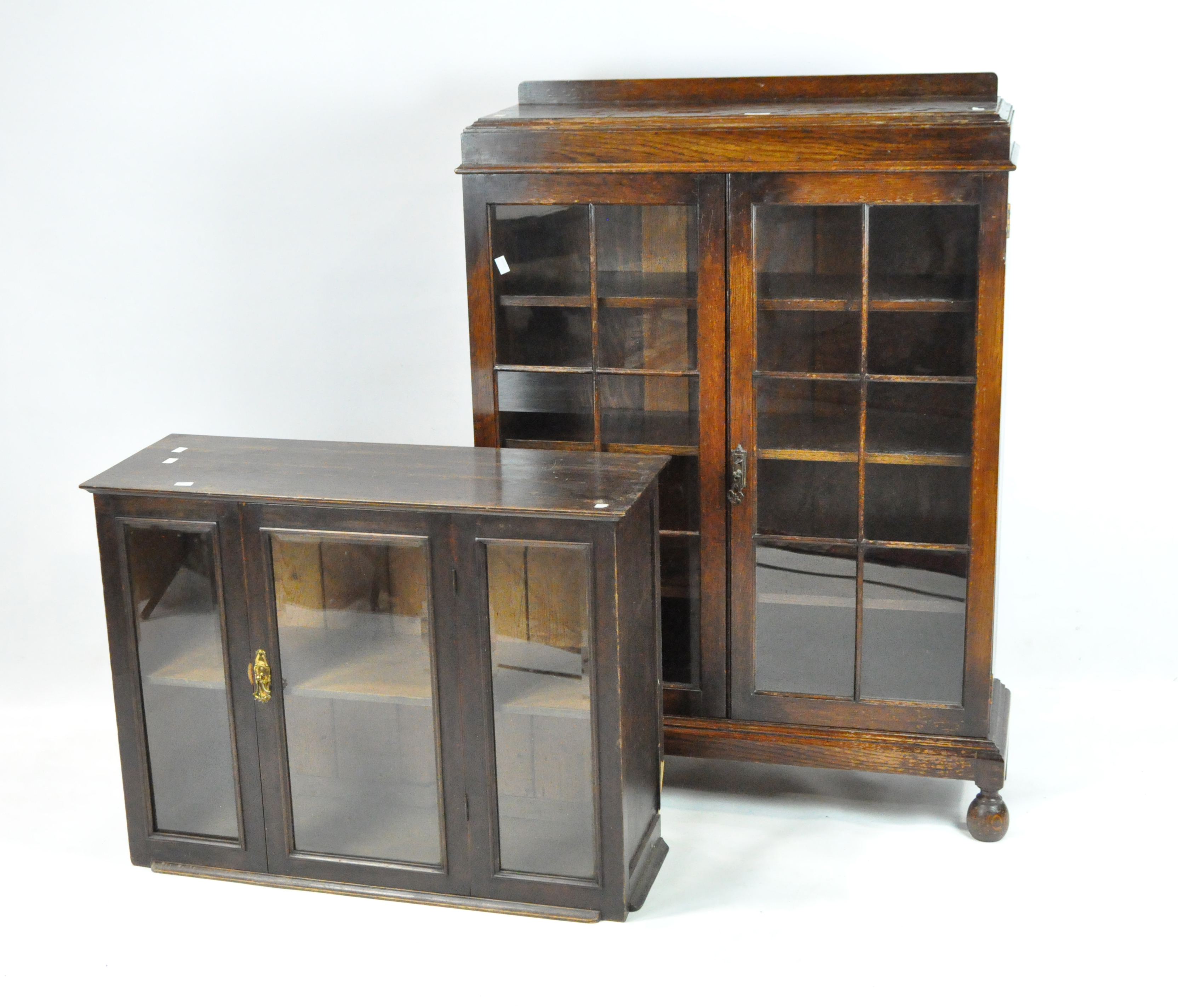 Two 20th century display cabinets, the larger of oak with three shelves behind glazed double doors,
