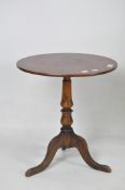 A Victorian mahogany wine table, the circular top placed on a baluster support with a tripod foot,