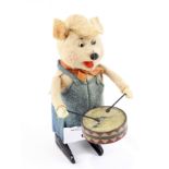 A Schuco clockwork toy in the form of a pig playing a drum, circa 1930s, height 11cm,