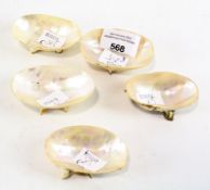 A collection of five mother of pearl open salt cellars, each raised upon three feet,