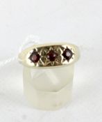 A contemporary 9ct gold three stone garnet ring, each within a starburst mount,