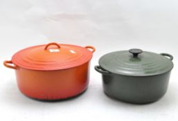 Two large enamel kitchen lidded pots in orange and dark green,