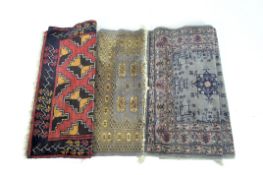 Three 20th century Eastern rugs, all with geometric designs and detailed borders,