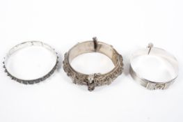 Three Omani style white metal bangle bracelets, some with filigree details,