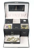 A black jewellery box containing a collection of costume jewellery, including brooches, necklaces,