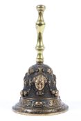 A late 19th/early 20th century brass bell, cast with female masks, swags and scrolls,