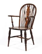 An elm country Windsor armchair, with pierced wheel back, on turned baluster legs,