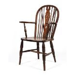 An elm country Windsor armchair, with pierced wheel back, on turned baluster legs,