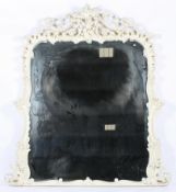 A large white painted carved overmantle mirror with scrolling rococo style decoration,