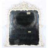 A large white painted carved overmantle mirror with scrolling rococo style decoration,