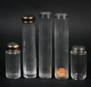 A collection of five Victorian and Edwardian silver topped glass dressing table bottles,