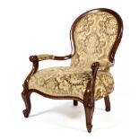 A Victorian mahogany framed upholstered spoon back armchair, with scroll carved arms,