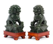 A pair of Chinese carved spinach green jade lion dogs seated on a pedestal, 20th century,