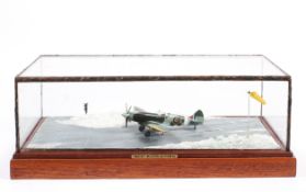 A glass cased scratch built diorama of a landing spitfire in a snowy scene