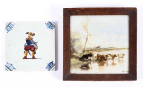 A 19th century Delft tile and another later, the first painted with cattle before a lake,