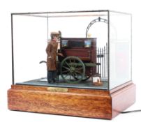 An electrified cased military diorama scene of an injured veteran in a glass case on wooden plinth