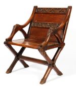 A late 19th century oak Glastonbury chair, carved with trefoil leaves to the panelled back,