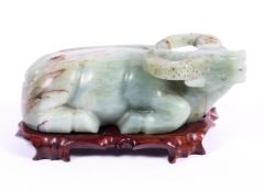 A Chinese carved jade model of a water buffalo on wooden stand, 20th century, modelled recumbent,