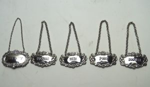 A collection of five silver decanter labels, comprising; Port, Scotch, Rum, Cognac and Sherry,
