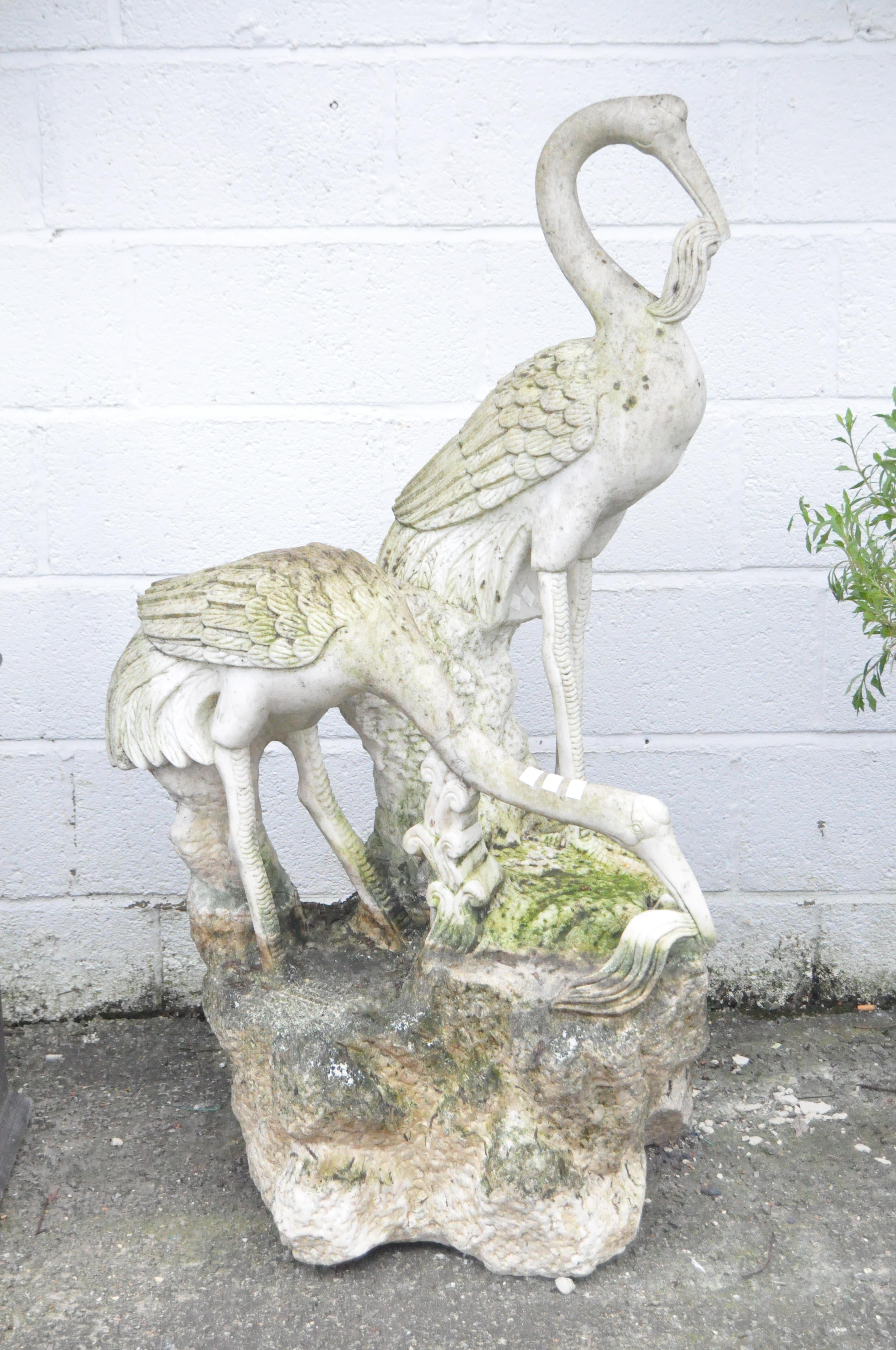 A large 20th century marble statue of two cranes standing on a rock,