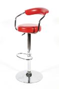 A chrome adjustable bar stool of tubular form upholstered in faux red leather.