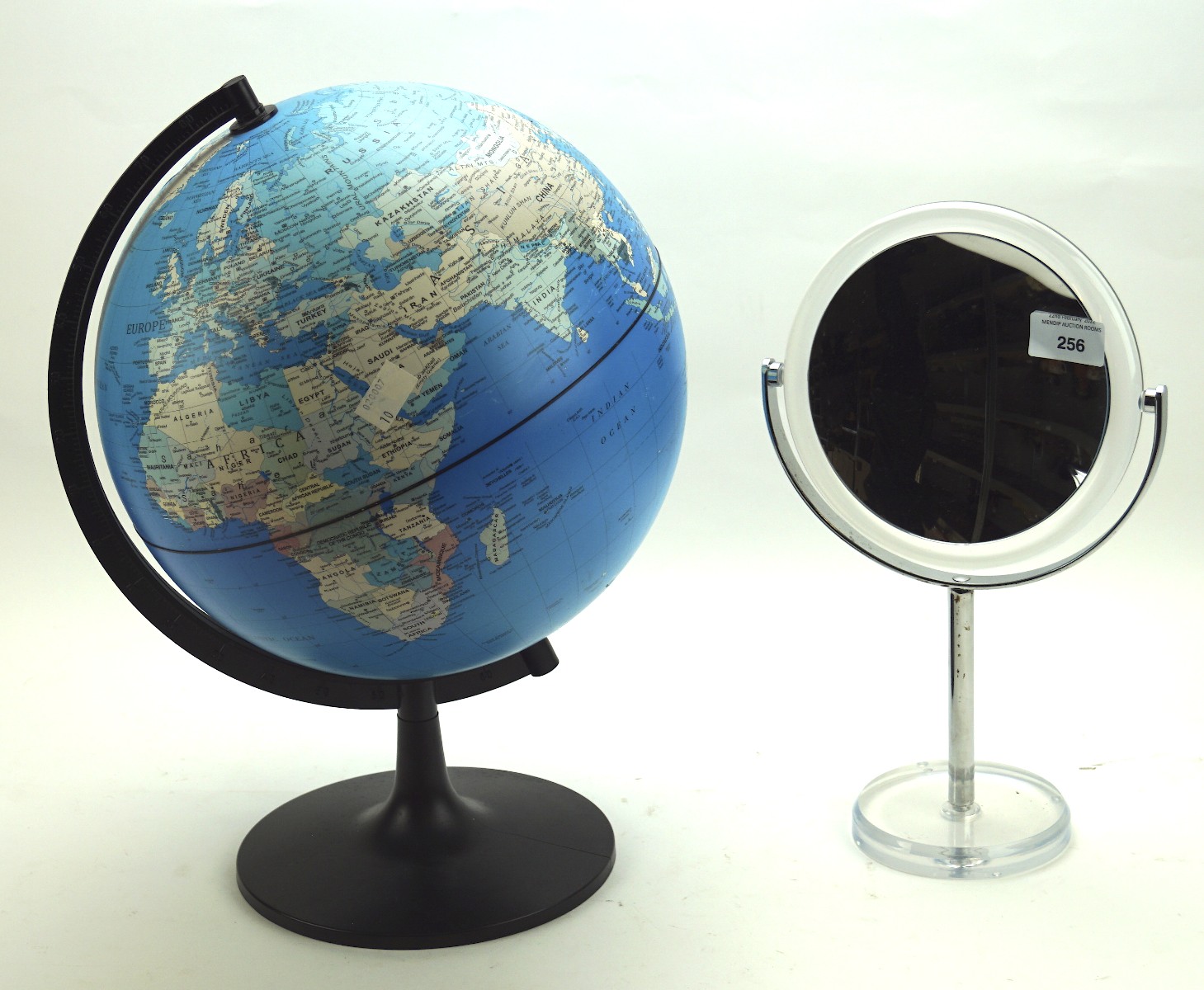 A contemporary magnifying bathroom mirror and a globe on a stand,