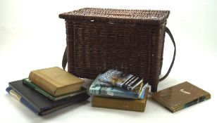 A wicker box containing a selection of books regarding fishing,