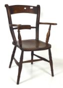 An early 20th century elm armchair, raised on turned tapered supports,