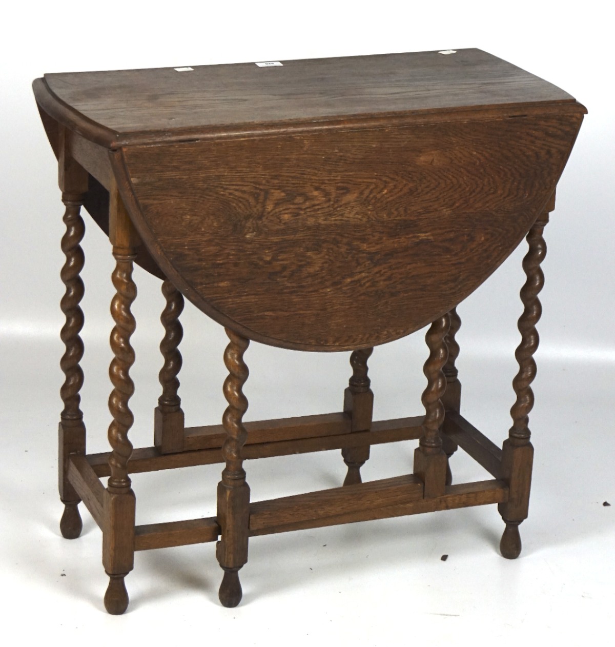 An oak drop leaf gateleg table, of circular form, on barley twist supports,