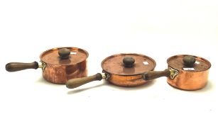 Three vintage metal saucepans, of graduating form, each with wooden handles,