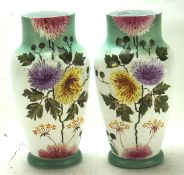 A pair of contemporary painted glass vases, decorated with flowers and foliage, on a circular base,