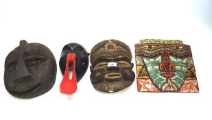 Four tribal wooden masks, each carved with a different design
