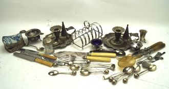 A collection of silver plate and metalware, including a candlestick, flatware, toast rack,