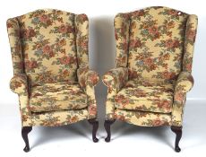 A pair of 20th century wing back armchairs, upholstered in a floral fabric,