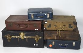 A travelling trunk and five vintage suitcases, the trunk in black with studded bindings, width 76cm,