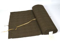 A large roll of tweed fabric, in green with blue, yellow and brown coloured threads,